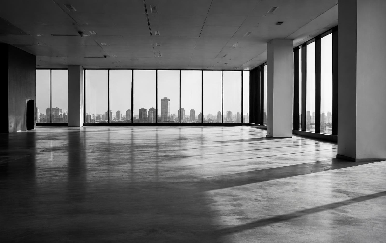 An empty modern commercial floor with floor-to-ceiling windows overlooking a city